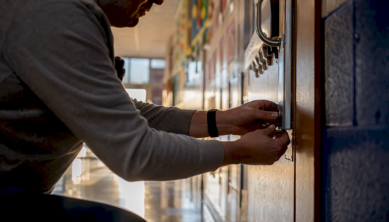 Staff member manually securing classroom door lock