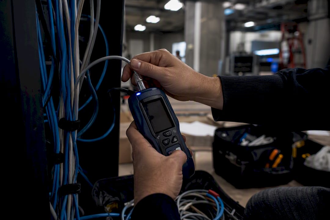 Hands testing security camera cable with a cable tester
