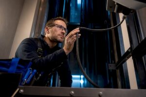 Technician inspecting elevator traveler cable wiring
